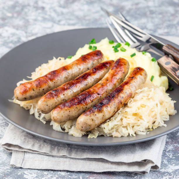 istock Roasted nuremberg sausages served with sour cabbage and mashed potatoes, on a gray plate, square 1191637887