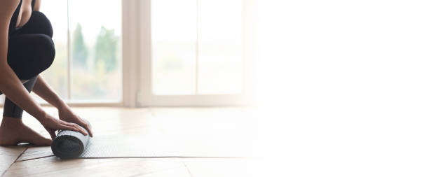 donna che inizia la sua giornata con la meditazione, srotolando tappetino yoga - unrolling foto e immagini stock