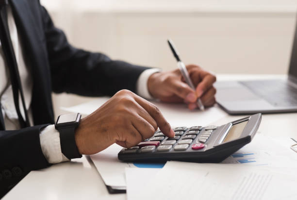 close up of man checking on incomes, using calculator - incomes imagens e fotografias de stock