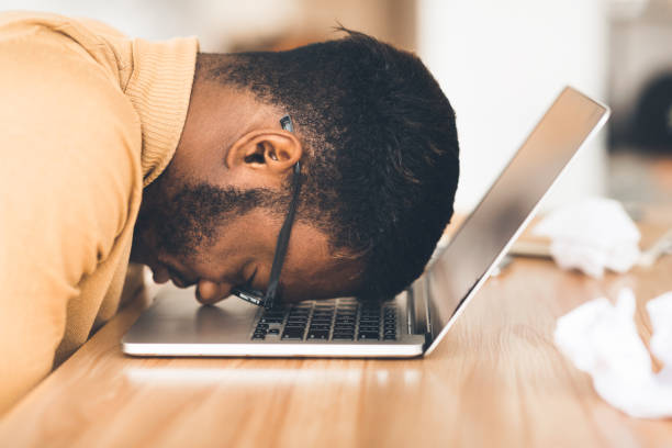 homme d'affaires surmené avec la tête vers le bas sur l'ordinateur - frustration computer men emotional stress photos et images de collection