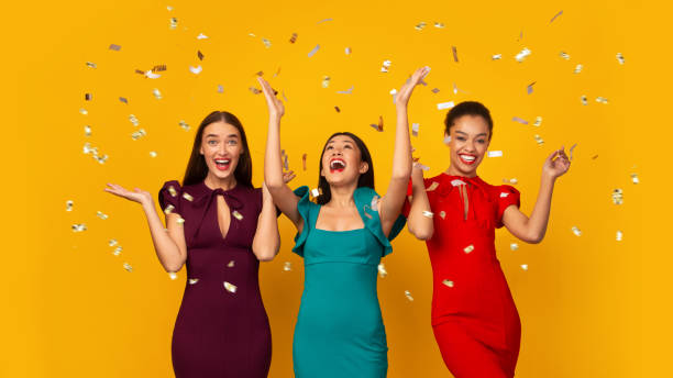 istock Three Multiethnic Girls In Dresses Having Fun Under Falling Confetti, Studio 1191643857