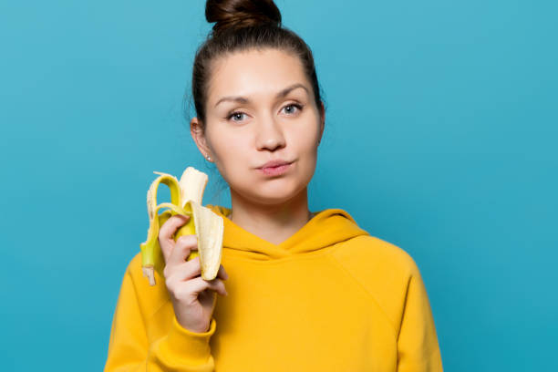 istock girl eats banana with pleasure 1191644233