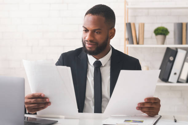 istock Black man in suit reading papers at his workplace 1191645653