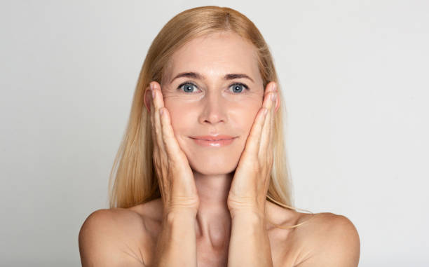 istock Anti aging treatment. Middle-aged woman touching cheeks 1191645704
