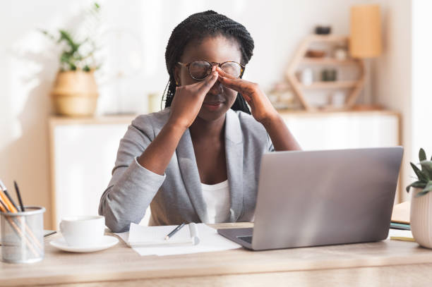 imprenditrice nera troppo lavoro che massaggia nosebridge sul posto di lavoro con problemi di vista - frustrazione foto e immagini stock