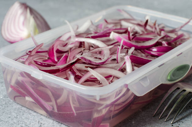 Pickled chopped red onion in vinegar in a plastic container. A delicious side dish for meat and fish dishes. Light grey background. Pickled chopped red onion in vinegar in a plastic container. A delicious side dish for meat and fish dishes. Light grey background. Side view vinegar stock pictures, royalty-free photos & images