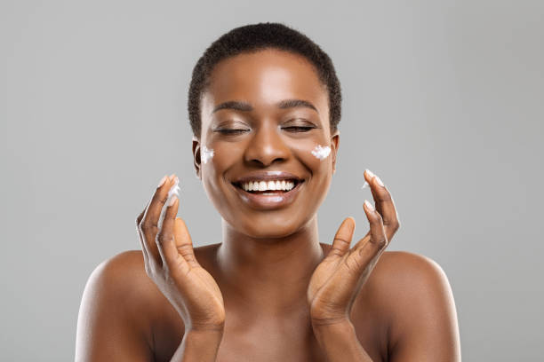 istock Beautiful afro woman applying cream on her cheeks and sincerely smiling 1191647541