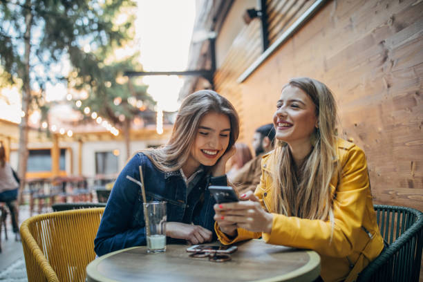 istock Young women using phone outdoors in cafe 1191647564
