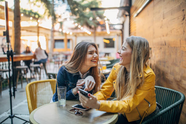 istock Young ladies using phone outdoors in cafe 1191647609