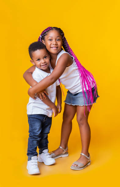 little black brother and sister cuddling and posing on yellow background - african ethnicity brother ethnic little boys imagens e fotografias de stock