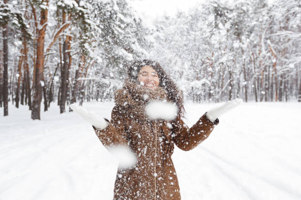 istock Cheerful Girl Throwing Snow Making Snowfall In Beautiful Forest 1191648494