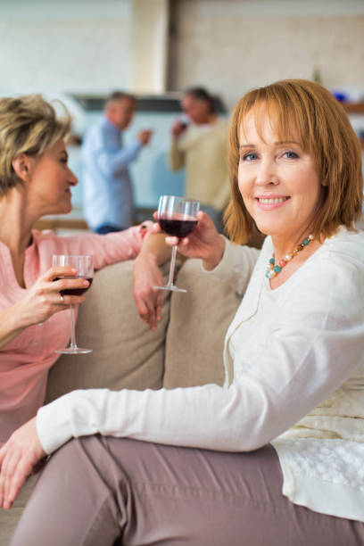 istock Mature women drinking wine while sitting in sofa at home 1191649079