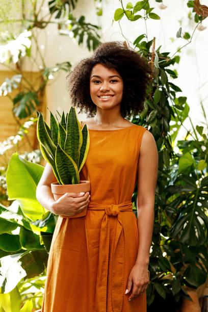 istock Young smiling botanist with pot in her hand standing at the botanical studio 1191649277