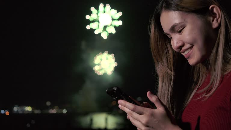 4K Slow motion New year festival Asian women She is using a mobile phone to photograph fireworks during the end of the year celebration.