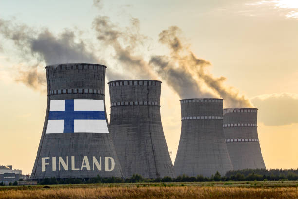 chaminés da planta nuclear que indicam a bandeira de finlândia com de acordo o texto. acidentes de poluição energética no conceito de país. produção de energia e geração a partir de energia atômica. - environment risk nuclear power station technology - fotografias e filmes do acervo