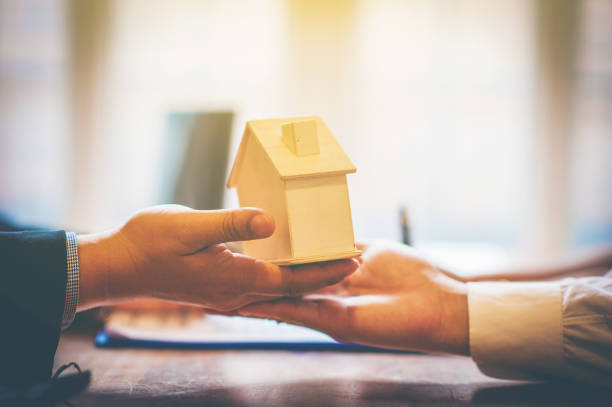 istock Businessman holding home model. 1191656783