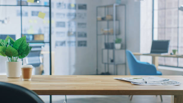 Wooden Desk in the Modern Creative Bright Office. In the Background Professional Computer