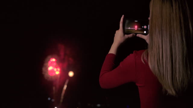 4K Slow motion New year festival Asian women She is using a mobile phone to photograph fireworks during the end of the year celebration.
