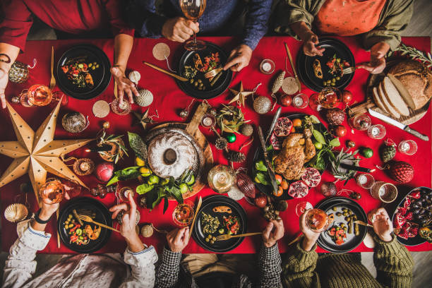 お祝いのクリスマステーブルで食べて話す友人のフラットレイ - holidays and food ストックフォトと画像