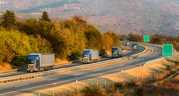 istock Convoy of five blue lorry trucks on a highway 1191665599