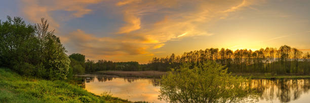 istock evening spring landscape. panoramic view of the river with a hilly grassy shore against a cloudy sky with a glow from sunset 1191669699
