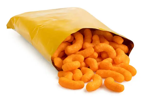 Photo of Open packet of extruded cheese puffs spilling out isolated on white.