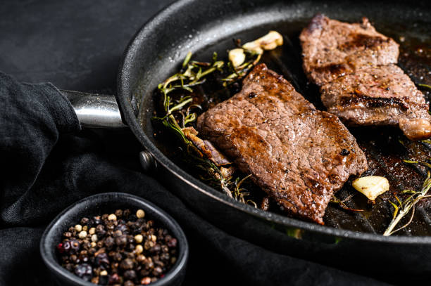 retirer le bifteck de longe dans une poêle. grillades. fond noir. vue du haut - steak meat strip steak restaurant photos et images de collection