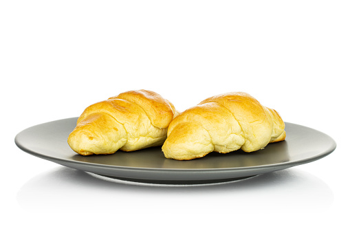 Group of two whole sweet golden mini croissant on gray ceramic plate isolated on white background