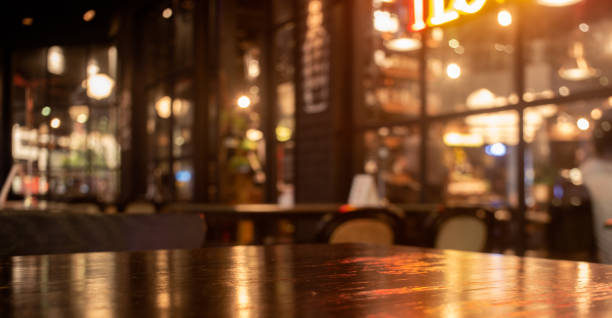 夜のレストラン、パブ、バーのシーンに光の反射を持つ空の本物の木製のテーブルトップ。 - カフェ ストックフォトと画像