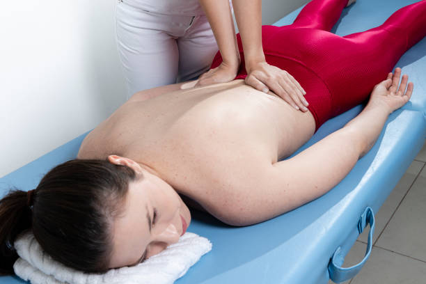 терапевт давая нижней части спины с�портивный массаж для спортсмена женщина пациента в клинике - physical therapy back table patient стоковые фото и изображения