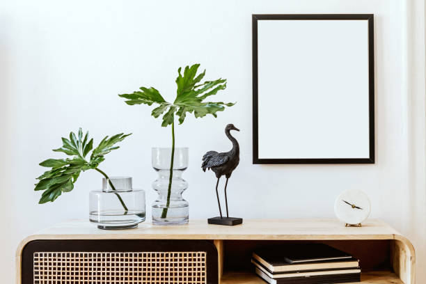 istock Modern scandinavian home interior with mock up photo frame, design wooden commode, black sculpture, tropical leaf, gray sofa and personal accessories. Stylish home decor. Template. Ready to use. 1191676477
