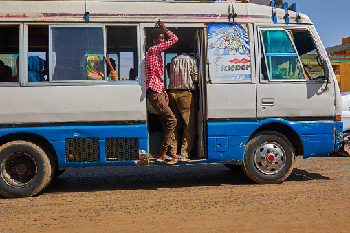 Khartoum, Sudan, ca. February 8., 2019: Passenger-operated minibus drives through the streets of Khartoum with doors open