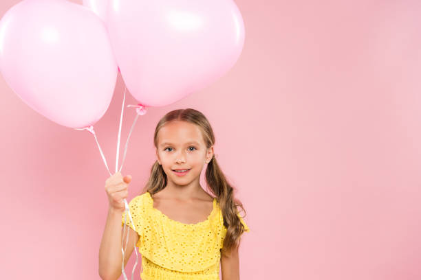 istock smiling and cute kid holding balloons on pink background 1191680587