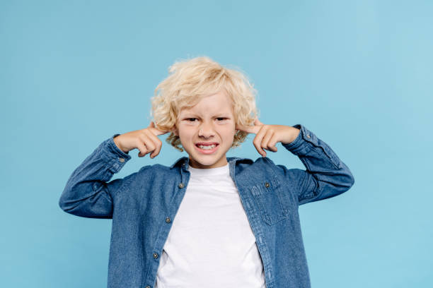 istock irritated and cute kid looking at camera and touching ears isolated on blue 1191680632