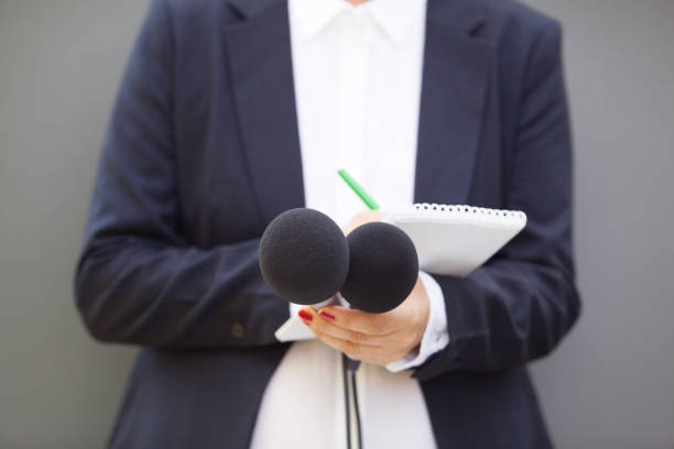 istock Journalist at news conference or media event, holding microphone and writing notes 1191681917