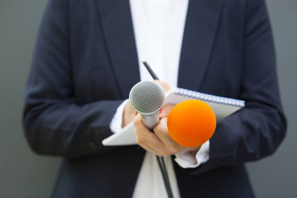 istock News reporter or journalist at press conference, holding microphone and writing notes 1191682680