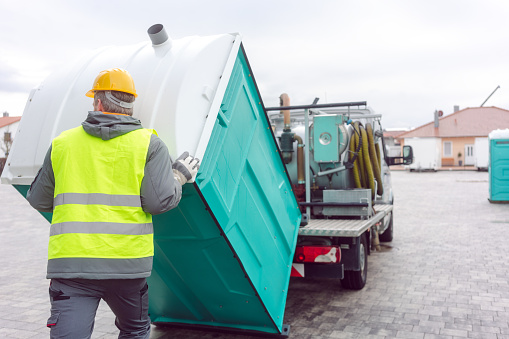 Rental lavatory being loaded on truck by worker