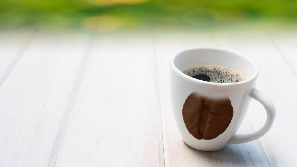 istock concept coffee brean print pattern on cup on white wood table. 1191689058