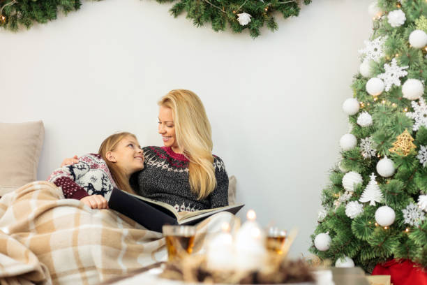 adolescente tumbado en el sofá con su madre, envuelto en una manta acogedora y mirando fotos en el álbum de fotos de la familia el día de navidad - 24403 fotografías e imágenes de stock