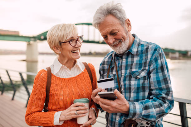 couples aînés ayant l'amusement par la rivière et faisant des emplettes en ligne - disposable cup coffee shopping friendship photos et images de collection