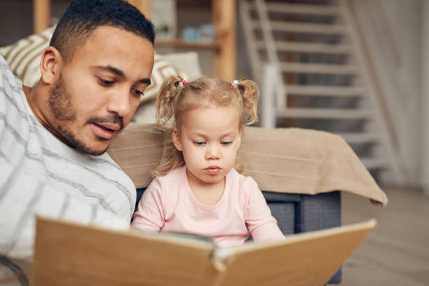 istock Father Reading Book to Cute Daughter 1191693293