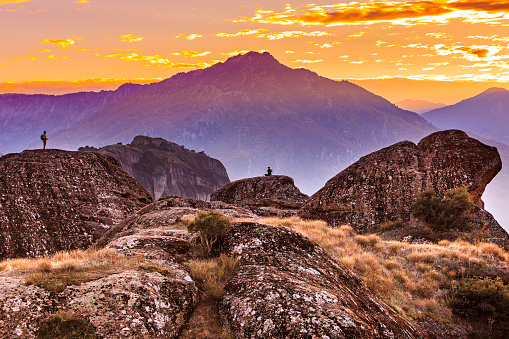 Tourists in mountains at sunset, two persons on cliffs rocky formations in Thessaly Greece. Tourism vacation and travel.