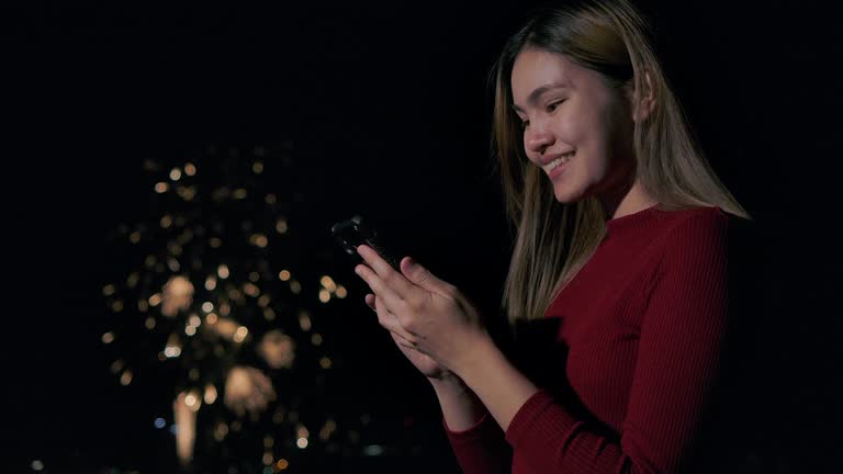 4K Slow motion New year festival Asian women She is using a mobile phone to photograph fireworks during the end of the year celebration.