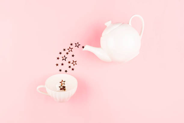Creative shot of star shape confetti pouring from tea pot into a cup. Flatlay, top view.