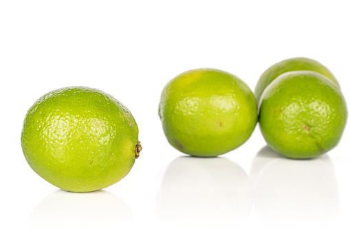 Group of four whole sour green lime isolated on white background
