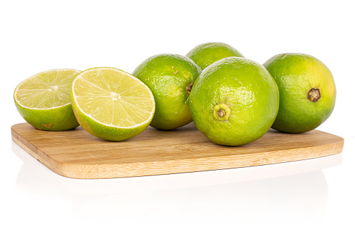 Group of four whole two halves of sour green lime on bamboo cutting board isolated on white background