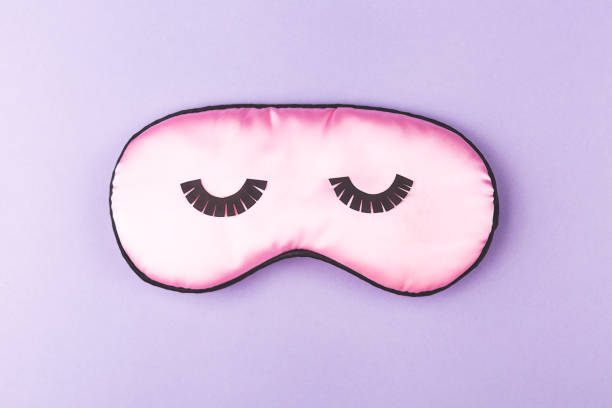 istock Pink sleeping mask on purple background. 1191696775