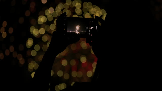 4K Slow motion New year festival Asian women She is using a mobile phone to photograph fireworks during the end of the year celebration.