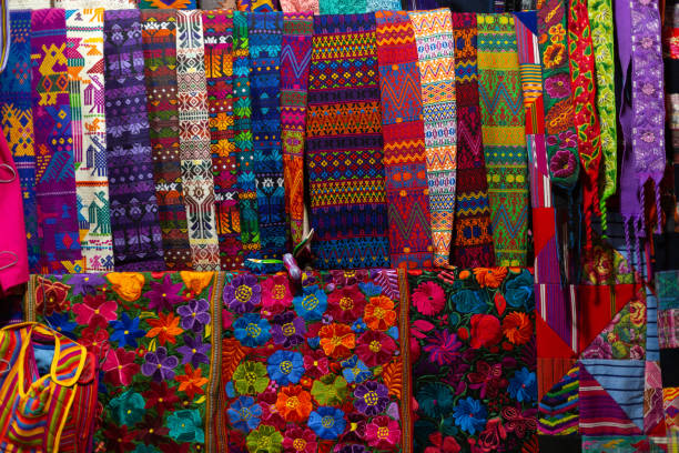 tessuti tipici guatemaltechi sparsi sul mercato- tessuti con disegni colorati di fiori tradizionali guatemaltechi - antigua guatemala - bedding merchandise market textile foto e immagini stock