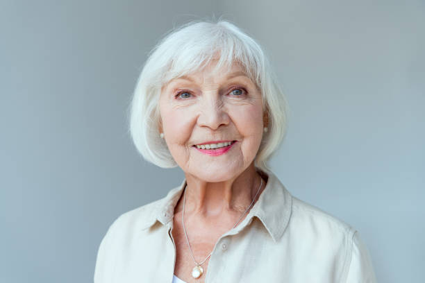 attractive and smiling woman looking at camera isolated on grey